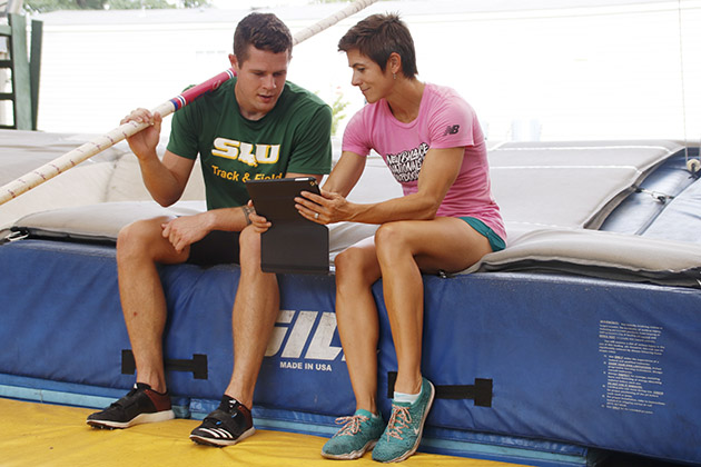Senior general studies major Devin King and his coach Erica Fraley review a video of his pole vaults during practice to spot areas of improvement. Fraley has been coaching pole vault for around 10 years. 