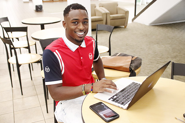 University alumnus Dwayne Woodard pauses from his work as a graphic designer to pose for a picture. Woodard is an entrepreneur with his business DOH Visuals LLC.