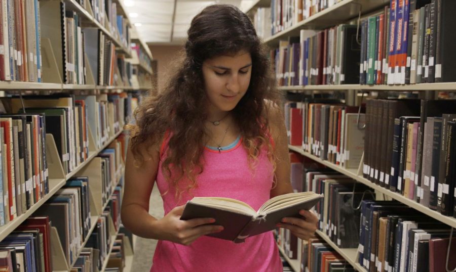 Nicole Zimmer, a senior biological sciences major, checks a book in the library. She has worked in the Sims Memorial Library for three years. 
