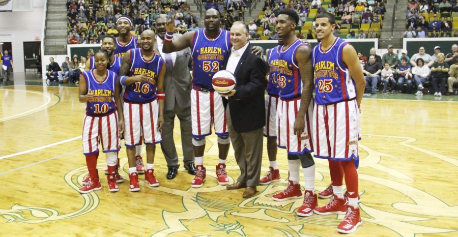 Jay Ladner, head coach of men’s basketball, poses with the Harlem Globetrotters including former player Nate Lofton in the University Center. Ladner aims to help his players reach their full potential as a coach. 