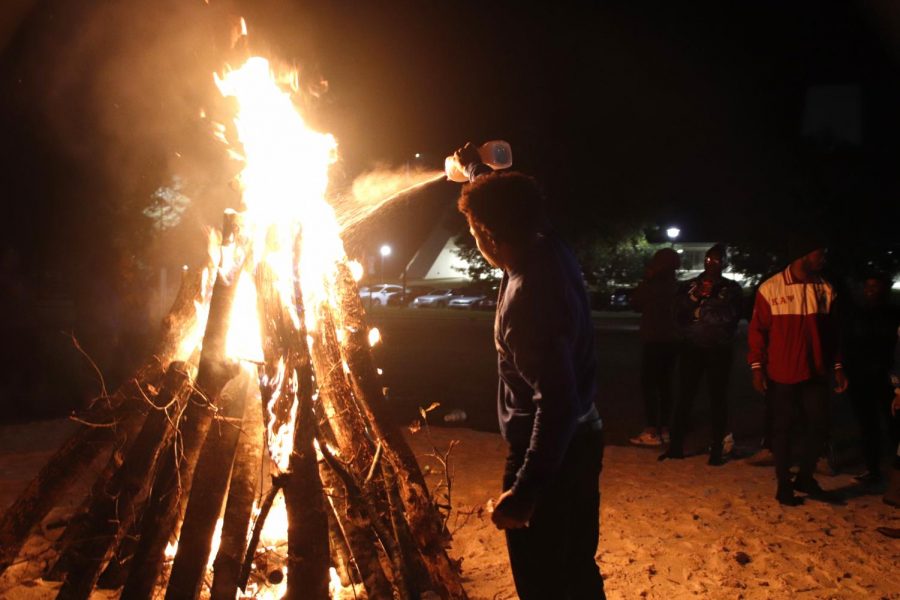 Anthony Page,  a member of Phi Beta Sigma,  fuels the fire at the BLUout Bonfire Nov.18.