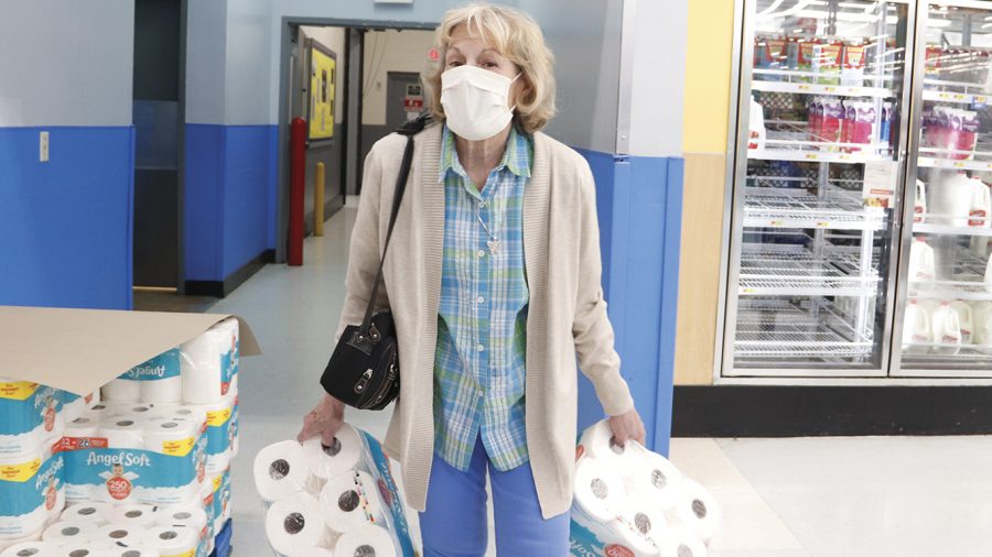A woman wearing a mask gathers items at Walmart, Monday, March 16, 2020, in Hammond. Toilet paper has become one of the much sought after items as many prepare for an extended “quarantine” at home. 