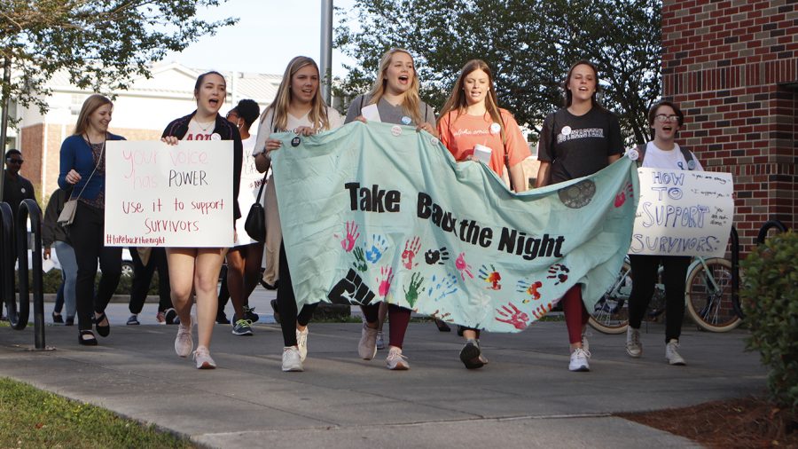 Students carry signs as they march around campus for Take Back the Night Rally. The event aimed to bring more awareness to sexual assault on college campuses.
