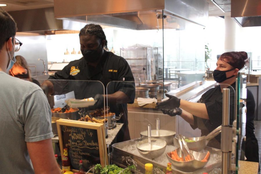 Mane Dish workers serve students buffalo wings with seasoned fries and their choice of sauces and vegetables.