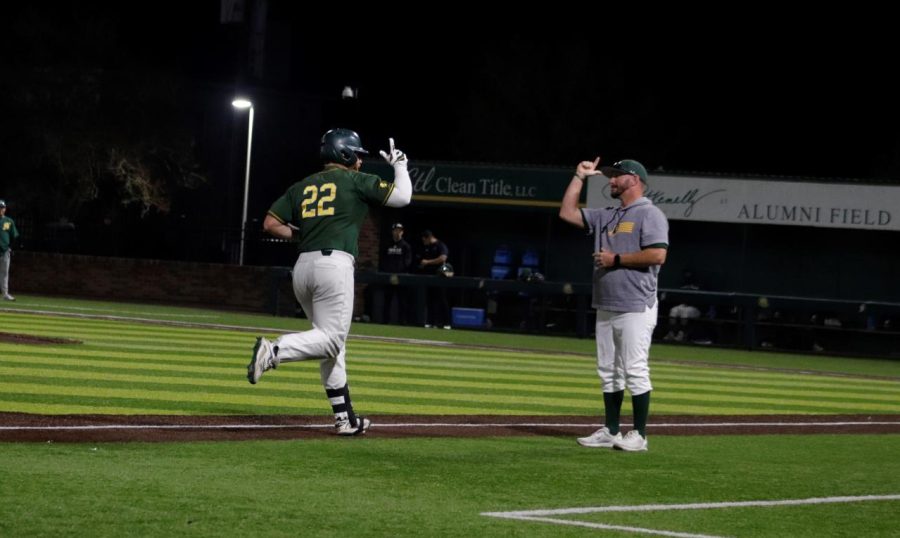 #22 Preston Faulkner gives Head Baseball Coach Matt Riser a Lion Up while rounding third base after smashing a home run in Game three of the Heart of a Lion series.
