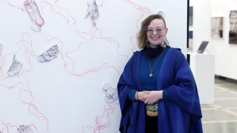 Sierra Arbaugh poses in front of their artwork, Subconscious Line.