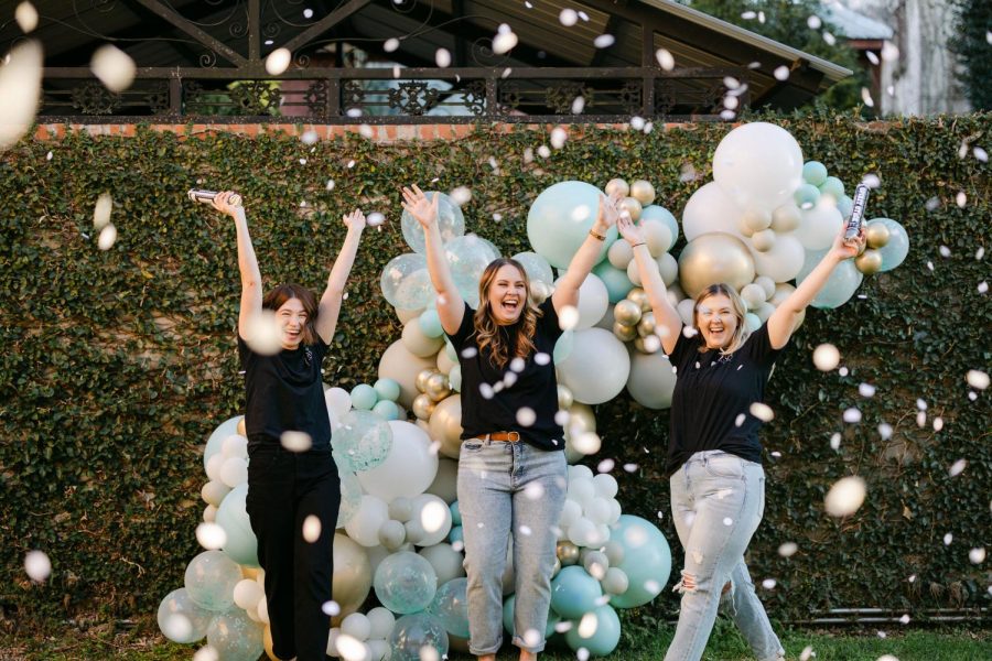 From left: Stephanie Neff, Jerica Fletcher and Hallie Laine smile with pride in front of one of their balloon displays while the confetti falls around them. The three ladies are on The Social Butterfly team.
