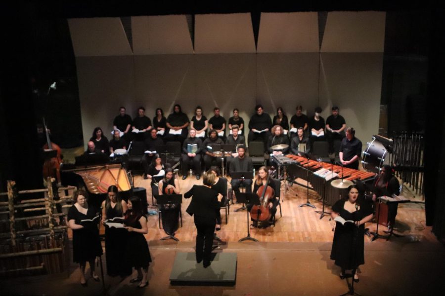 Members of the Concert Choir singing upfront near the microphone along with the choir behind them. Students would often get up throughout the performance for solos or to give the audience a piece of information about the Matthew Shepard case. 