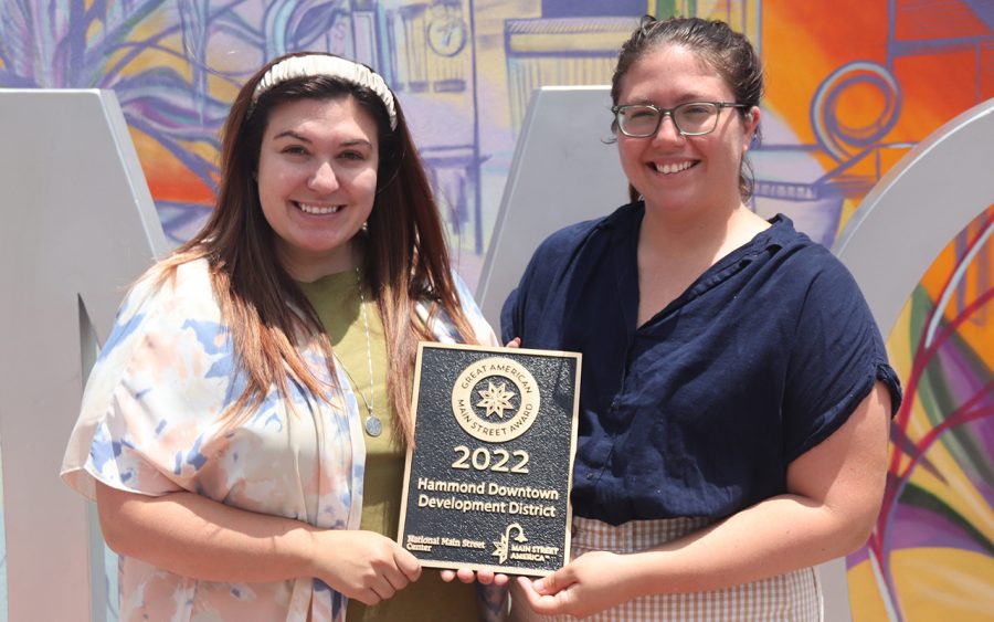 Hammond Downtown Development District Executive Director Chelsea Tallo Little and Community Health & Farmers Market Manager Michelle Kendall stand in front of Downtown Hammonds new mural with the GAMSA award.