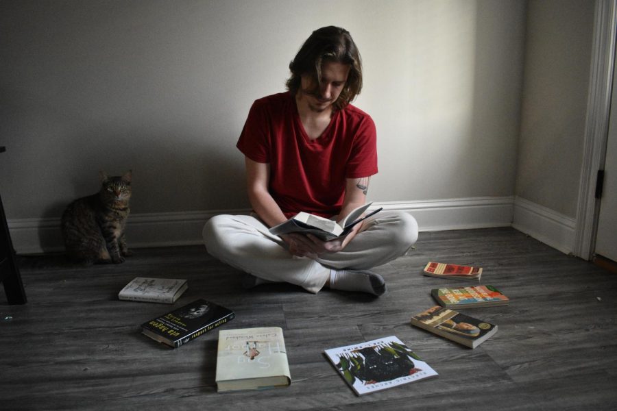 A student surrounded by books bought over the semesters.  To save money, students can look toward Sims Memorial Library or their local libraries to borrow books. 