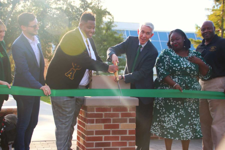 Dr. Crain and members of NPHC cutting the ribbon at the opening ceremony of their plot dedication. This project has been in the works for five years and can now be seen at Student Union park.