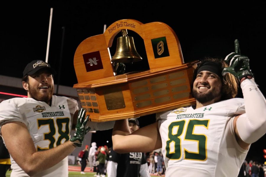 Ivan Drobocky (left) and Tanner Olsen (right) hoist River Bell Classic Trophy after SLU defeated Nicholls 40-17 on Thursday night in Thibodaux to clinch the Southland Conference Title. (Nov 17, 2022)