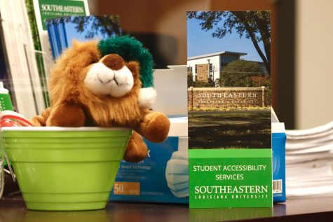 A brochure of Student Accessibility Services is featured alongside a miniature, multicolored Southeastern lion. 