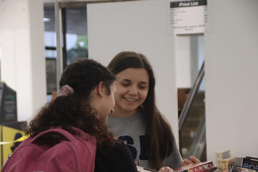 Two students perusing books in the lobby of Sims Memorial Library. 