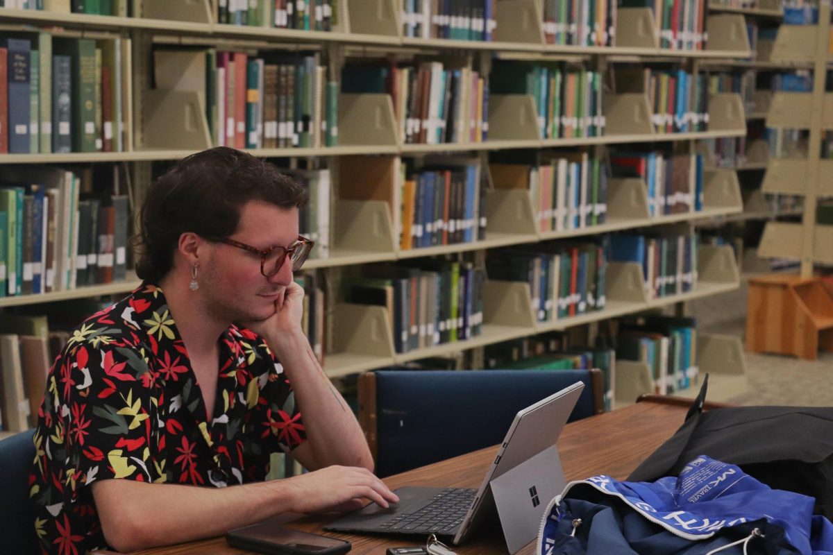 A student is studying amongst the shelves of the fourth floor of Sims Memorial Library. Many students find that the quiet environment of the library helps them focus and relax. 