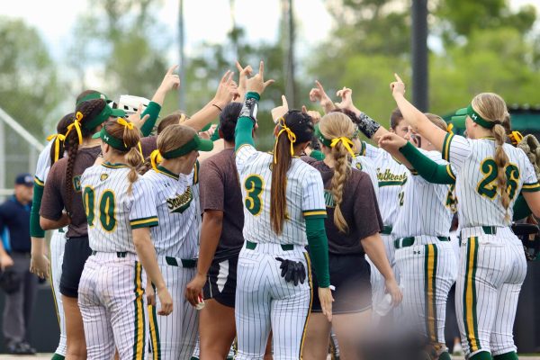 Softball huddling up with outreached hands as they celebrate their victory against HCU on Friday. (March 23, 2024- Pat Kenelly Diamond at Alumni Field – Hammond)
