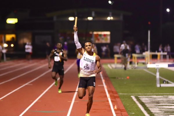 Former Lion Eugene Omalla raises baton triumphantly as he approaches finish line to secure a first-place finish for SLU in the 4x400 meter men's relay at the 2023 Southland Conference Championships. (May 6, 2023 - Commerce, Texas)