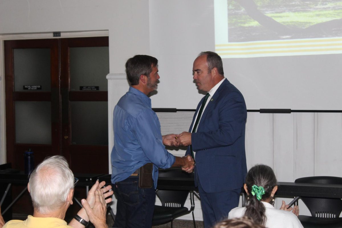 Assistant Director of Physical Plant Services for Landscape and Grounds Carlos Doolittle accepts his medal from Dr. Wainwright.