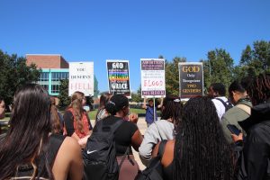 Students gather around the banners and engage in discussions with the members of Consuming Fire Fellowship Church.