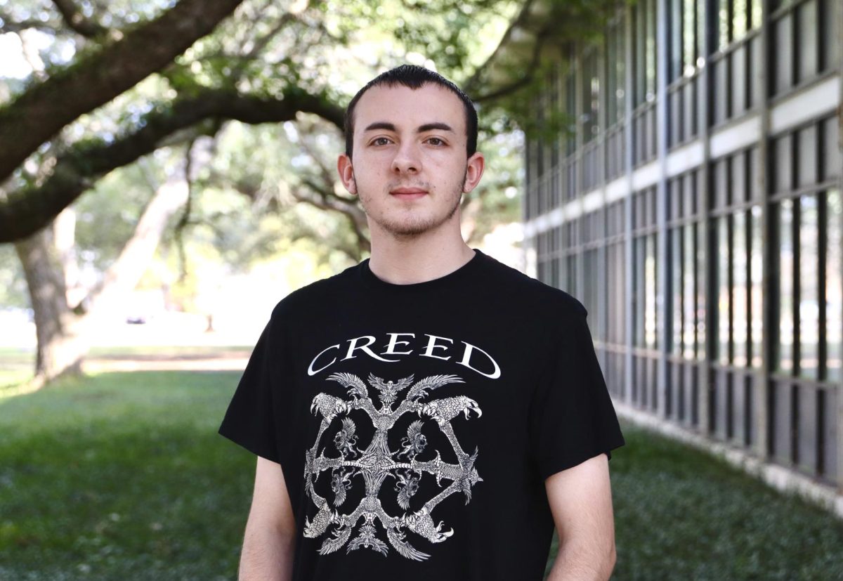 A man with a black shirt poses with a blurry background