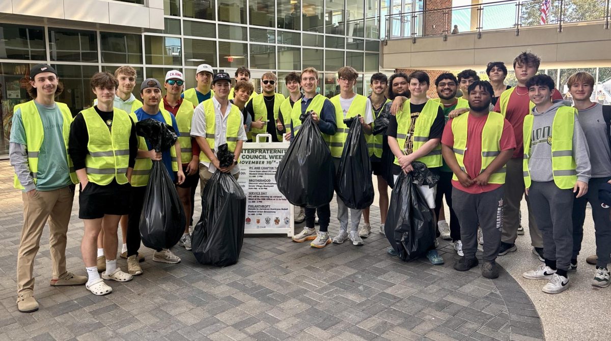 A group of young men in caution vests hold trash bags in a breezeway.
