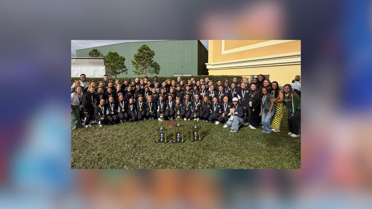 Group of people sitting behind trophies.