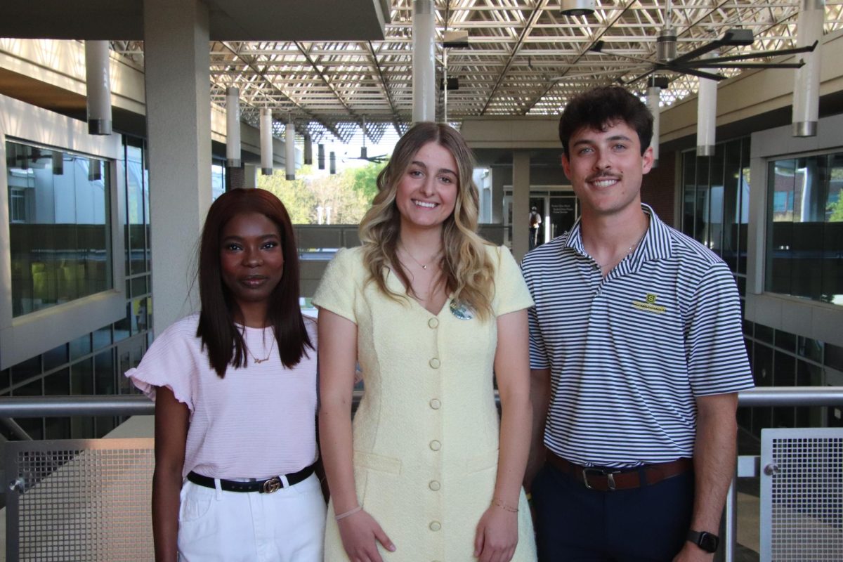 Three people stand on a balcony.