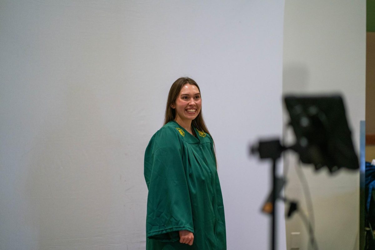 a woman posed with a green graduation gown