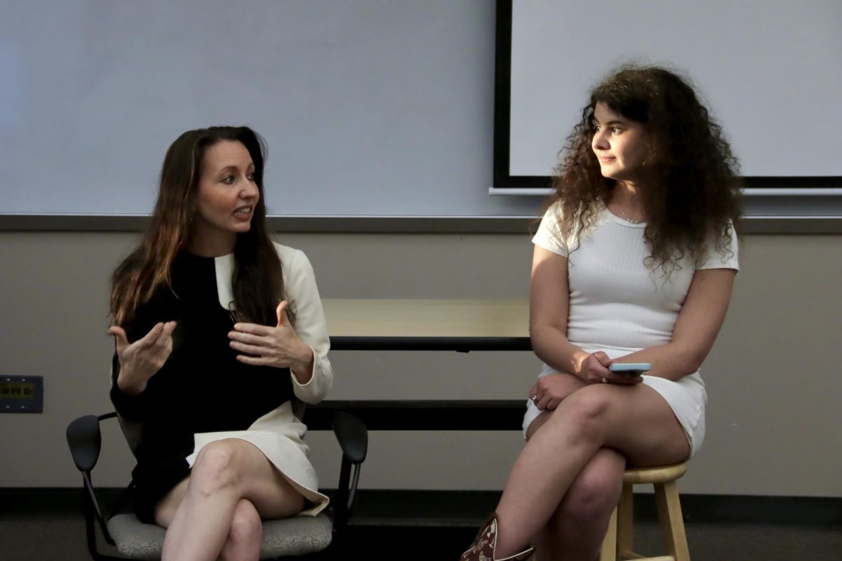 Two women sitting and speaking to eachother.