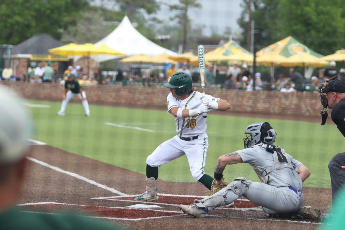 A baseball player ready to swing as the ball is pitched towards him.